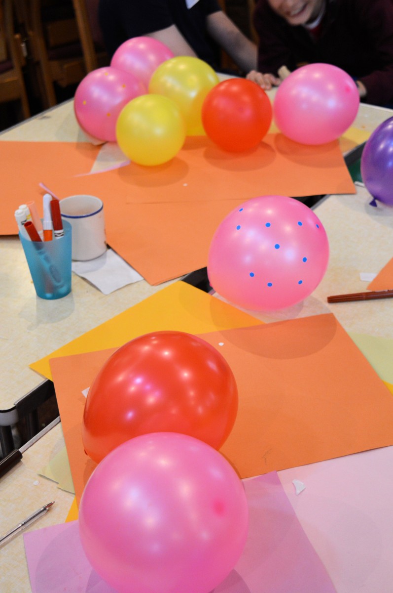 Picture of balloons, coloured paper and pens on a table